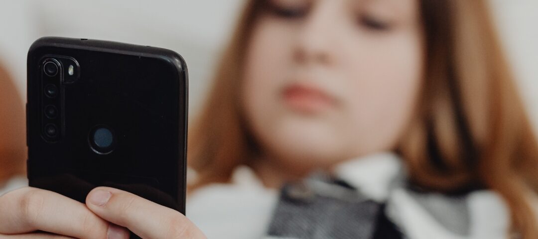 Ragazza seduta sul divano mentre scorre i social dal telefono